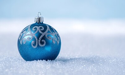 Blue christmas bauble with glittery silver design decorating white snow, symbolizing winter holidays and festive season