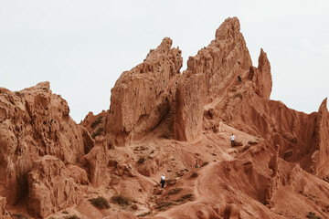 Fototapeta premium Travelers Exploring the Rugged Cliffs of Skazka Canyon, Kyrgyzstan
