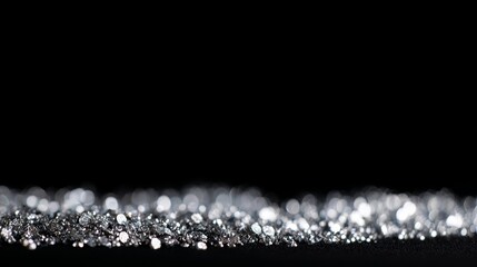 Silver glitter bokeh on black background, sparkling metallic light particles creating festive and elegant abstract effect, suitable for celebration, luxury, glamour, and decorative design projects