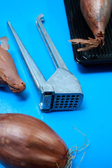 Metallic garlic press on blue background