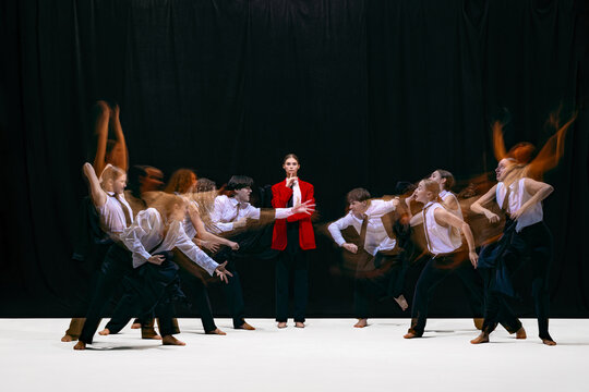 Still leader in red jacket surrounded by blurred dancers representing tech-driven distraction. Concept of digital attention, smartphone influence, behavior patterns and modern media culture.
