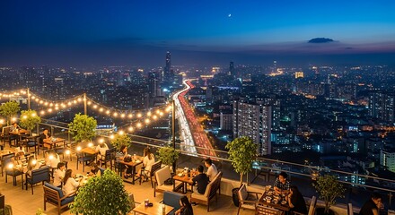 Obraz premium Lively rooftop bar with string lights overlooking a vibrant city skyline at dusk.