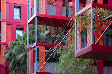 Modern architecture housing in Montpellier France with a red facade, vegetation, afternoon light, strong color contrast and distinct structural lines