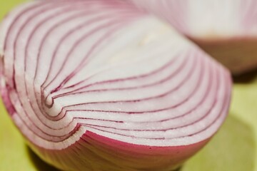 Slices of red onion, sometimes called "Bermuda onion" on a green plastic cutting board