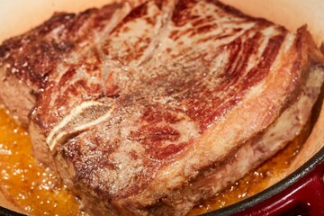 A chuck steak browing in a Dutch oven