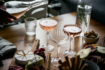 Pouring rose wine with classic snacks of cheese, bread and olives. Party or anniversary celebration.