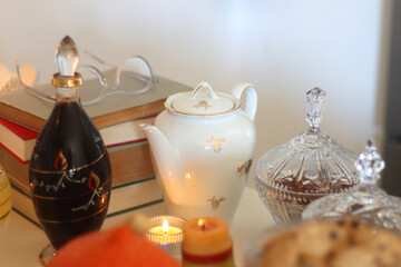 Lit candles, cookies, chocolate, nuts, tea, wine, pumpkins, books, reading glasses and autumn leaves on the table. Autumnal hygge at home. Selective focus.