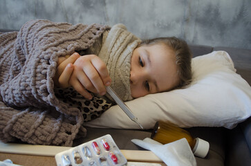 A little girl is lying in bed sick. The concept of illness, cold, acute respiratory viral infection