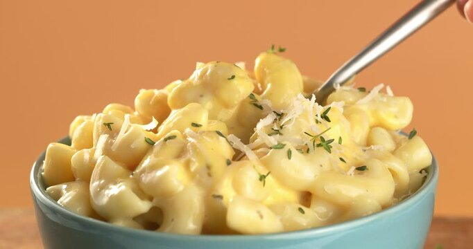 Fork picking up Mac and Cheese with herbs and Parmesan. Close-up footage of pasta.
