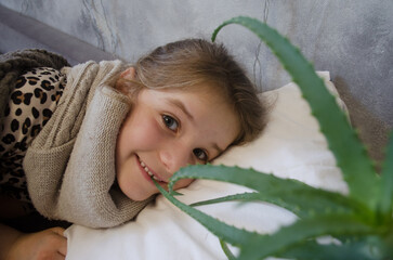 A little girl is lying in bed sick. Aloe Vera Cold Cure
