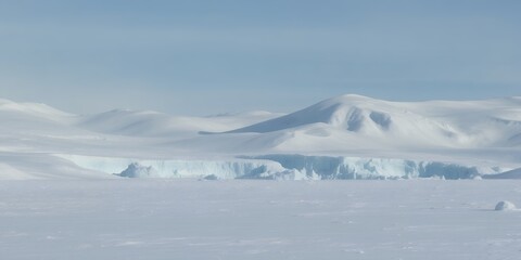 Expansive view of glacial cliff face and snow covered rolling hills across frozen polar wilderness landscape under pale sky