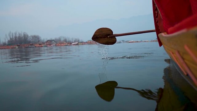 Close up shot of heart shaped wooden paddle moving Shikara boat on Dal Lake at foggy winter morning in Srinagar, Jammu and Kashmir, India. Travel, tourism and holidays concept. Wooden boat in Dal lake