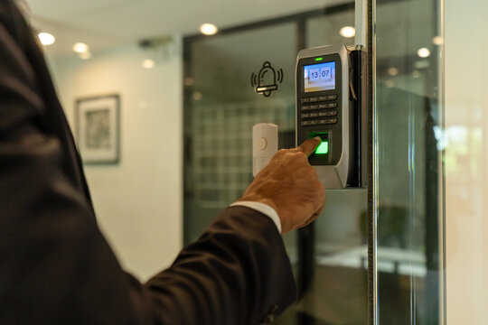 Hand of employee touch fingerprint scan of biometric attendance machine security login logout of office, finger press on digital door lock technology sensor to access restriction area