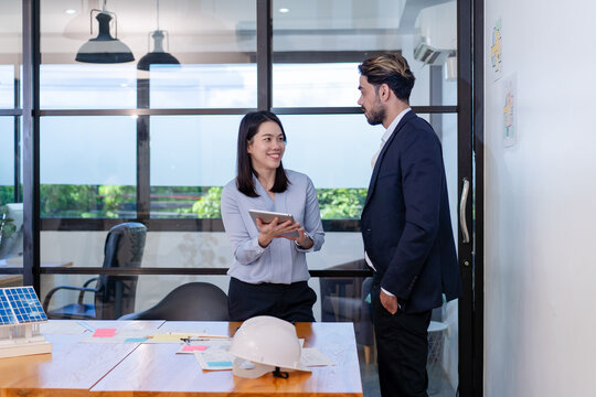 business manager colleague discuss budget topic in creative green office co-working space, team of business people coworker casual online meeting on tablet standing desk modern office workplace