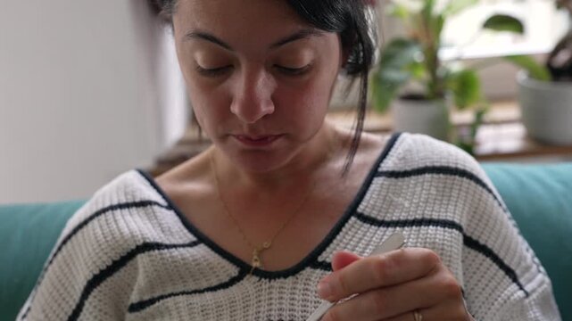 Close view of woman eating scrambled eggs with fork while holding white plate during relaxed indoor meal