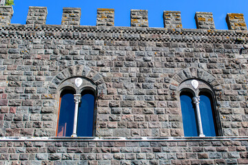 Mura del castello di Torre Alfina con due finestre bifore e merli guelfi con cielo