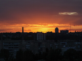 Dramatic sunset over city skyline with vibrant orange and red hues. The sun sets over a city, painting the sky with fiery colors and silhouetting buildings