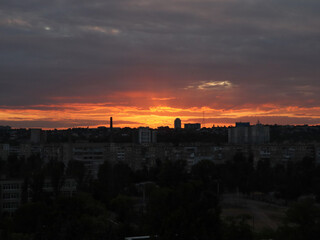 Dramatic sunset over a city skyline with colorful clouds and buildings. The vibrant colors of the sunset illuminate the city, creating a beautiful and awe-inspiring scene