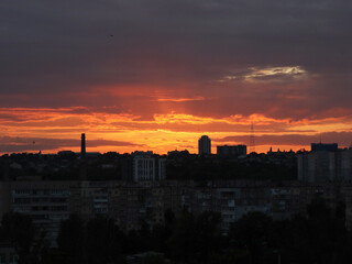 Dramatic sunset over a city skyline with colorful clouds and buildings. The vibrant colors of the sunset illuminate the city's silhouette, creating a stunning visual display