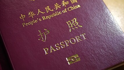 A slow, deliberate camera movement across the official cover of a People's Republic of China passport, highlighting its details.