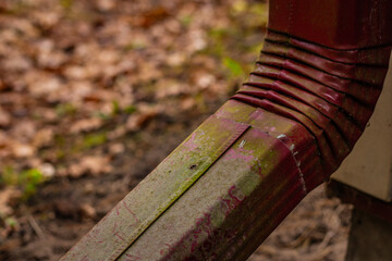Detailed image of a bent red metal downspout showing signs of aging and exposure to the elements....
