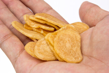 Holding uncooked shrimp crackers, isolated on white background. These crackers are later fried and served as a side dish, usually eaten with rice and other dishes as the main meal.