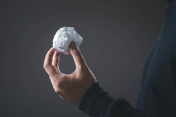 A hand holding a crumpled paper ball, symbolizing discarded ideas, creative failure, revision,...