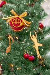 Close up of Christmas tree with musical and ballet ornaments, red cherries, and string lights. Festive decoration for holiday celebration