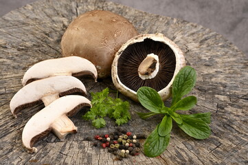 Fresh mushrooms - champignons, with parsley and pepper on a wooden background.
