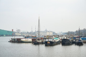 Fototapeta premium A group of boats are docked in a harbor Amsterdam in Netherlands, with some of them being small