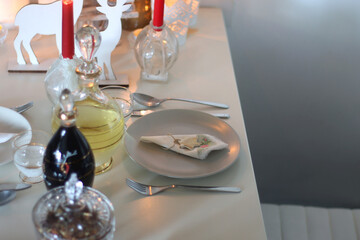 Table set for Christmas meal, with plates, wine, decorations and lit candles. Selective focus.