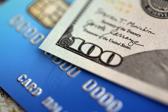 One hundred US dollar bill banknote on blue credit card for banking and payments. Concept of business and bank service