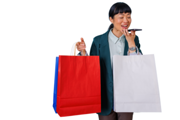 Asian woman speaking into smartphone holding colorful shopping bags, sending voice message enjoying retail therapy, transparent background