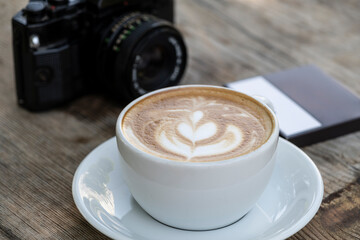 Latte coffee and camera on wooden table. Warm latte and vintage camera still life. Photographer’s coffee break with latte and camera.