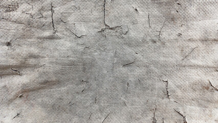 Close-up texture of a gray, dirty, non-woven fabric or industrial textile with fine cracks and rough edges. Ideal abstract background for grunge, industrial, decay, paper, scrap