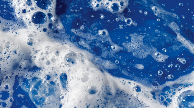 Close-up of white soap lather forming large and small bubbles on smooth blue surface, light reflecting off the foam for vibrant cleaning visual