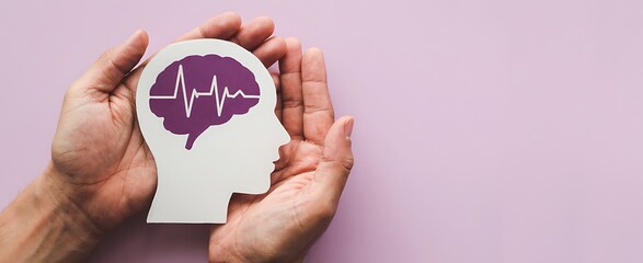 Hands gently cradling a paper cutout of a human head silhouette with a vibrant purple brain and heartbeat ekg line inside symbolizing mental health awareness and neurological care