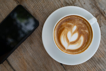 Coffee and smartphone on wooden surface. Coffee cup and smartphone on table. Mobile phone with coffee cup lifestyle scene.