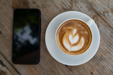 Coffee and smartphone on wooden surface. Coffee cup and smartphone on table. Mobile phone with coffee cup lifestyle scene.
