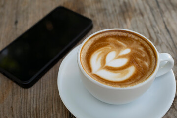 Coffee and smartphone on wooden surface. Coffee cup and smartphone on table. Mobile phone with coffee cup lifestyle scene.