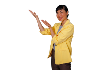 Young asian woman wearing a yellow jacket, smiling, and confidently gesturing with both hands, presenting a concept on a transparent background