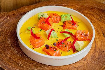 Salmon and avocado cubes are artfully arranged on a smooth, creamy sauce in a cozy setting