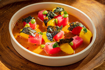 Fototapeta premium Fresh watermelon, mango, and avocado cubes complemented by a rich broth and seaweed