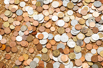 Various coins rest upon a textured surface, highlighting unique designs and diverse origins