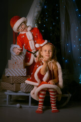 Happy kids dressed as Santa Claus enjoying festive holiday magic on a sled stacked with colorful presents.