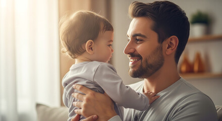 Smiling father holding his baby son in living room near window, sharing a loving moment of connection and joy at home.