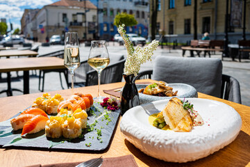 Delicious sushi varieties are served alongside glasses of white wine in a lively outdoor atmosphere