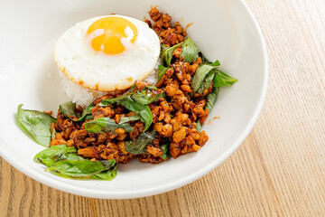 A savory dish of stir-fried chicken and basil topped with a sunny-side-up egg and rice