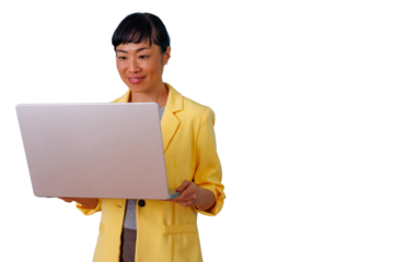 Asian businesswoman smiling and working on a laptop, standing with a yellow blazer, using modern technology