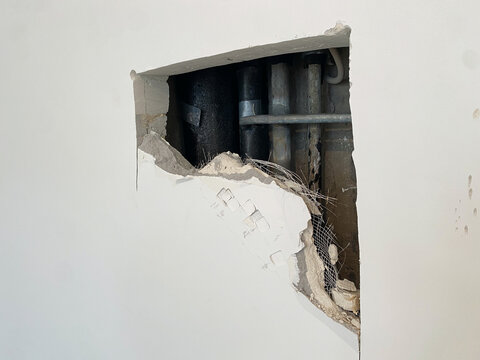 Hole, pipework repair. Problem during renovation or construction. No access panel in wall to see riser. Old rusty waste stack,. To access pipes and fix emergency leak, wall had to be broken down